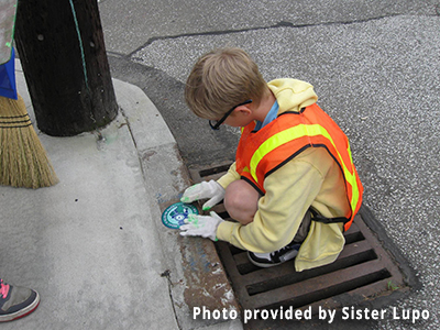 A child puts an awareness sticker on a storm drain.