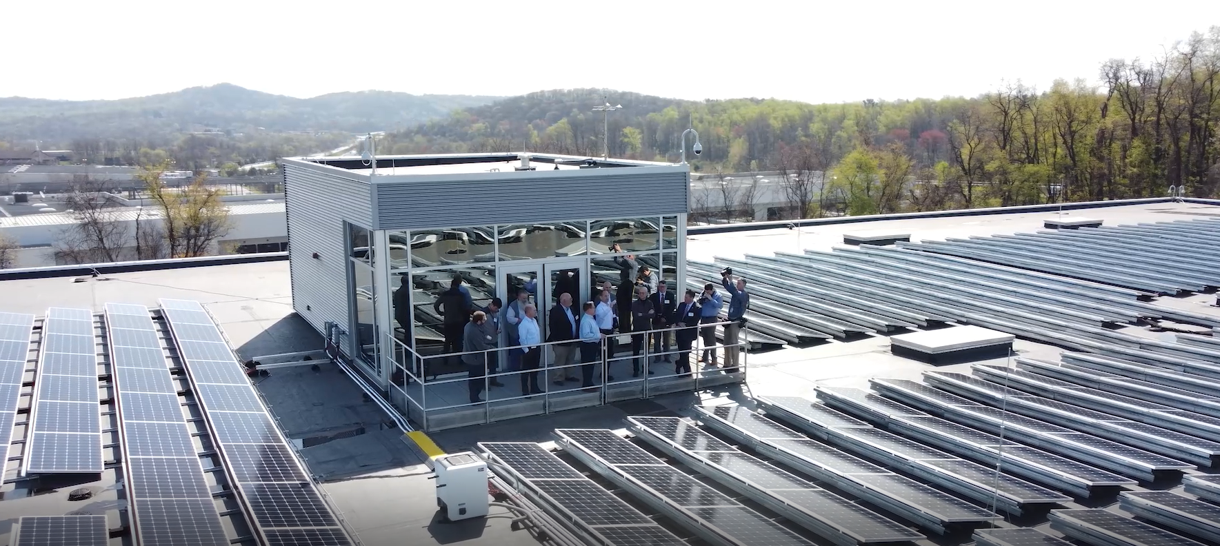 A group stands on top of the roof by solar arrays