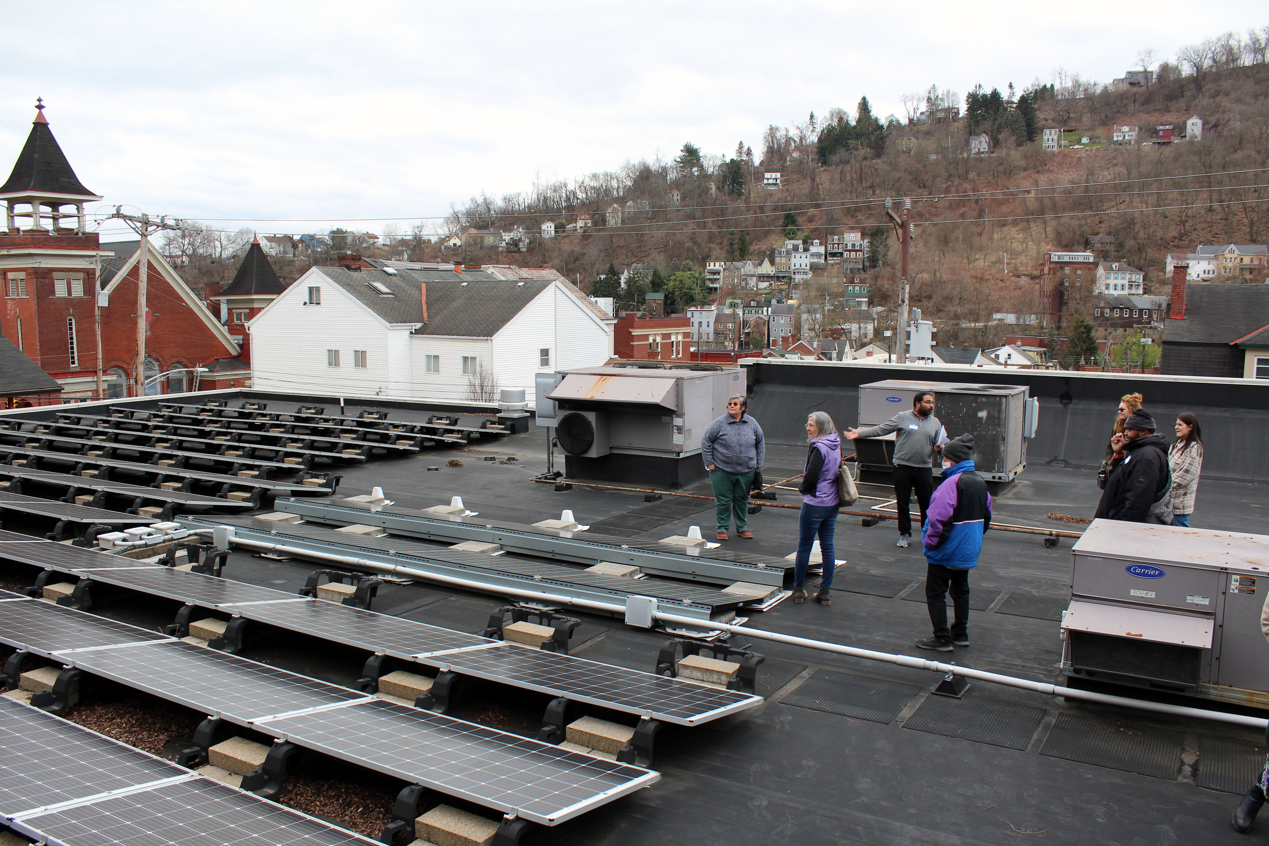 People stand on a roof with solar panels