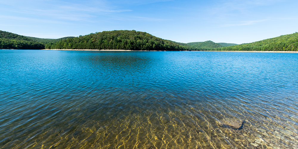 Clean water in a reservior in Pannsylvania with blue sky and tree-covered mountains