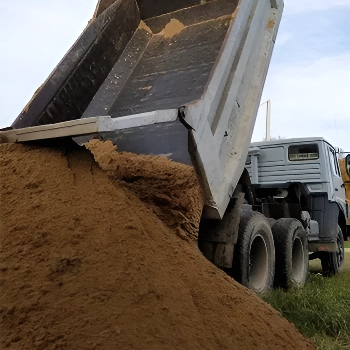 A truck unloads a pile of fill dirt