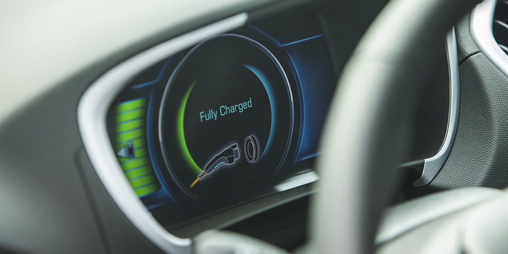 An electric vehicle dashboard shows the vehicle is fully charged