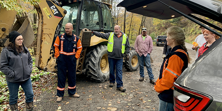 Volunteers hold a safety meeting next to heavy equipment