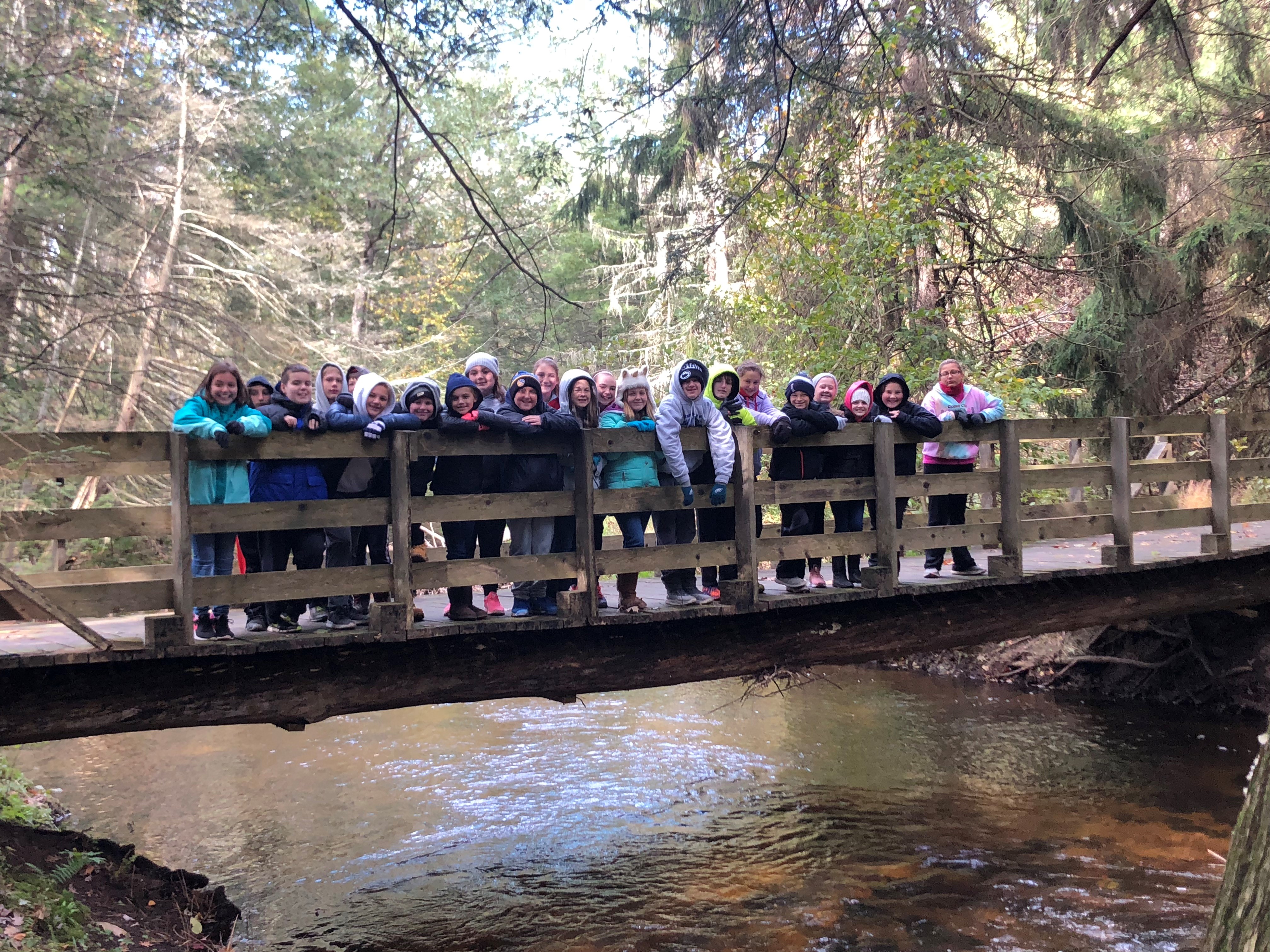 Students pose for a group photo on a bridge over a stream